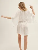 Bata color blanco con estampado de lunares, mangas largas y lazo para ajustar en la cintura.