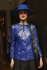 Campera azul de cuero ovino italiano, con cuello redondo, cierre frontal con broches ocultos, bolsillos laterales y detalle de capitoneado en puños y bolsillos.