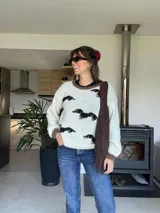 Sweater tejido color crudo con cuello y puños marrones, con diseño de perros salchicha marrones.