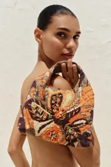 Bolso de mano con cuerpo cubierto de abalorios y bordados multicolores. Tiene asa de mano doble y correa metálica extraíble para usar como bandolera. El cierre es imantado.