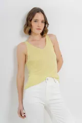 Musculosa tejida color amarillo pálido, con escote en V delantero y trasero.