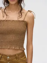 Top corto negro con textura fruncida, tirantes finos con lazos ajustables y corte crop.