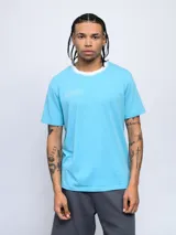 Remera celeste de corte clásico con cuello redondo blanco y logo Umbro estampado en el pecho.