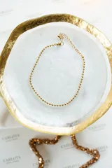 Tobillera dorada de acero quirúrgico con cadena de bolitas.