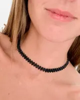 Choker negro ajustado al cuello, compuesto por pequeñas piedras negras engarzadas en un patrón de zigzag o rombos.