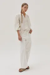 Blusa blanca de algodón con hilos metalizados, cuello mao y escote en V.