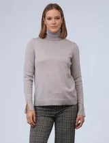 Polera tejida de hilado fino, color beige claro, de manga larga y cuello tortuga. Presenta un tajo en el puño de la manga.