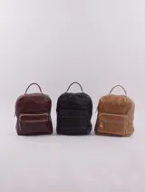 Mochila de cuero color marrón claro, con múltiples bolsillos externos con cierre y aplique trasero para colocar en carry on.