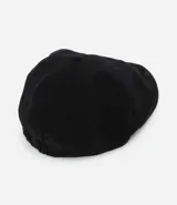 Boina color beige confeccionada en sarga, con una pequeña asa en la parte superior y cierre de elástico.