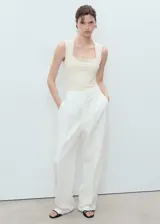 Top sin mangas color crema, de tejido elástico y diseño entallado, con escote cuadrado y tirantes anchos.