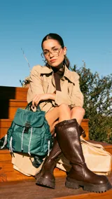 Mochila verde militar de nylon con tapa y broche metálico. Tiene apertura superior con cierre marinero, bolsillos internos, bolsillo con cierre metálico al frente y laterales. Incluye asas rígidas de mano y correas regulables para colgar en la espalda.