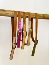 Cinto de cuero con punta en colores variados y hebilla metálica rectangular.