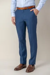 Pantalón de vestir azul de lino, corte clásico, con bolsillos laterales y traseros. Se ajusta a la cintura con cinturón de cuero marrón.