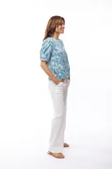 Blusa celeste con estampado de flores blancas, mangas cortas abullonadas y cuello redondo.