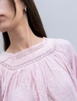 Blusa rosa claro de algodón con escote cuadrado, manga larga y bordado floral en el frente y las mangas.