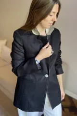 Blazer de lino color blanco con solapas y cuello en color beige, corte entallado, botón de nácar, tajo en la espalda y bolsillos laterales.