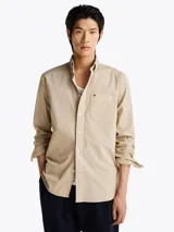 Camisa beige de corte amplio confeccionada en sarga de puro algodón teñido en prenda. Tiene cuello con botones, bolsillo de parche en el pecho y puños redondeados con botón.