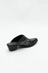 Zuecos negros de cuero sintético con punta fina, bordados en la capellada y taco cuadrado de 5cm de alto.