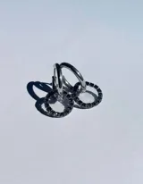 Par de aros colgantes con argollas doradas y dijes circulares de resina transparente con incrustaciones de strass de colores. El dije mide aproximadamente 1.5cm de diámetro.