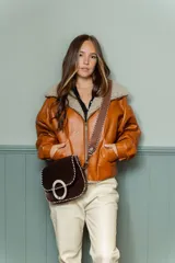 Chaqueta bomber color marrón de cuero sintético con cuello de piel sintética color beige.