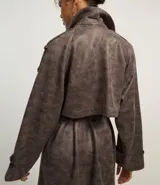 Trench coat largo color marrón con efecto teñido, cuello inglés, manga larga, cierre doble con botones delanteros y cinto para lazo en la cintura.
