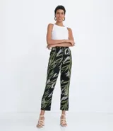 Pantalón pijama fluido de viscosa con estampado de hojas en tonos verde y gris sobre fondo negro. Tiene cintura media con ajuste de cordón con punteras metálicas, bolsillos laterales y pinzas frontales.