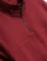 Buzo de color bordó con cierre en el cuello y diseño clásico.