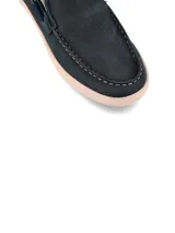 Mocasín de cuero color marrón con cordones decorativos y suela blanca.