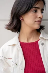 Chaqueta blanca de jean con cuello clásico, cierre frontal con botones metálicos y bolsillo de parche en el pecho. Presenta detalles de piedras de colores en el canesú.