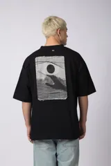 Remera negra de corte oversize con cuello redondo y mangas cortas. Estampado pequeño en el frente y parche estampado en la espalda.