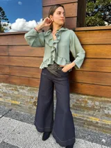 Blusa verde agua con cuello camisero con volados, mangas largas con puños elásticos y corte a la cintura.