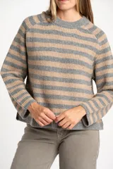 Sweater de tejido de punto con diseño de rayas horizontales alternando gris y beige. Presenta cuello redondo y mangas largas con costura decorativa visible en los laterales.