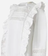 Blusa blanca de tricolina con volados en los laterales, cuello redondo, cierre por gota, mangas abullonadas largas y entremedios en el busto y en las mangas.