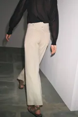 Jeans de tiro alto, pierna ancha y largo al tobillo, en denim celeste claro con efecto lavado. Presenta costura marcada en el centro de cada pierna y cierre frontal con cremallera y botón.