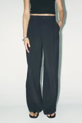 Pantalón negro de tiro alto con cintura con trabillas, bolsillos laterales y de vivo en espalda, pernera recta y cierre frontal con cremallera y botón. Confeccionado en hilatura con modal.