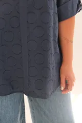 Blusa azul marino con diseño de puntos en relieve, escote en V con botón de nácar y mangas 3/4 con botón para ajustar el largo.