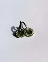 Par de aros colgantes con argolla de acero quirúrgico, dije circular de resina negra y borde de strass plateado.