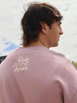 Buzo de algodón color lila con cuello redondo y calce holgado. Estampado en el frente con la frase "Ride the Wave".