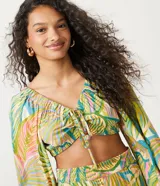 Blusa cropped de viscosa con estampado tropical de follaje, escote en V con lazo, mangas largas con elástico y bajo ajustable.