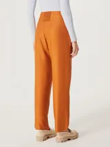 Pantalón de vestir color naranja, de corte recto y tiro alto, con pinzas en la cintura.