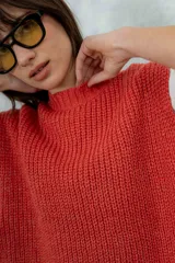 Chaleco de punto grueso color coral, con cuello alto y sisas amplias.