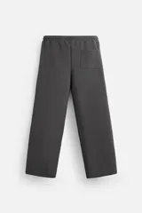 Pantalón jogger wide fit color gris oscuro, confeccionado en tejido de algodón compacto con elasticidad. Cuenta con cintura elástica ajustable con cordón, pliegues frontales, bolsillos delanteros y bolsillo trasero de parche.