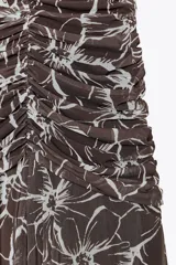 Vestido largo marrón con estampado de flores blancas, cuello halter con lazada, detalle de frunces y forro interior combinado.