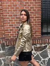 Chaqueta plateada metalizada con cuello camisero, cierre frontal con botones, bolsillos de parche en el pecho y corte recto.
