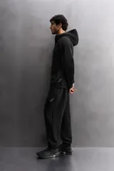 Pantalón jogger color marrón oscuro, corte regular fit, confeccionado en tejido técnico compacto de algodón con elasticidad. Cuenta con cintura elástica ajustable con cordón, bolsillos frontales y bolsillo lateral con cierre de cremallera.