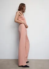 Pantalón de vestir color salmón, de corte wide leg, con pinzas delanteras y bolsillos laterales. Cierre frontal con botón, gancho y cremallera.