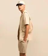 Bermuda masculina color crema, de tejido con textura sutil, cintura elástica con cordón de ajuste y bolsillos laterales.