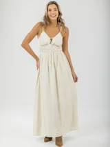 Vestido largo color crema, de breteles finos regulables, con guarda trenzada en la cintura y elástico en la espalda.