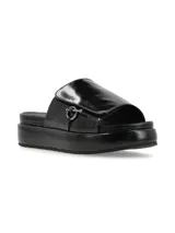 Sandalia de cuero color negro con tira ancha sobre el empeine, ajuste con velcro y aplique metálico circular.