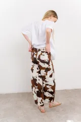 Pantalón ancho de lino con estampado de manchas de vaca en tonos marrón y blanco. Incluye cinturón de soga trenzada con flecos.
